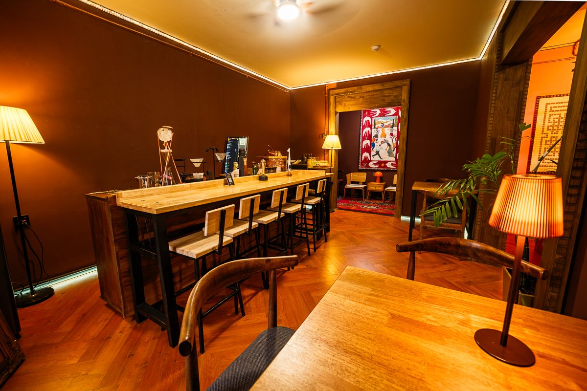 Bar counter view toward a lounge area with a woven wall hanging